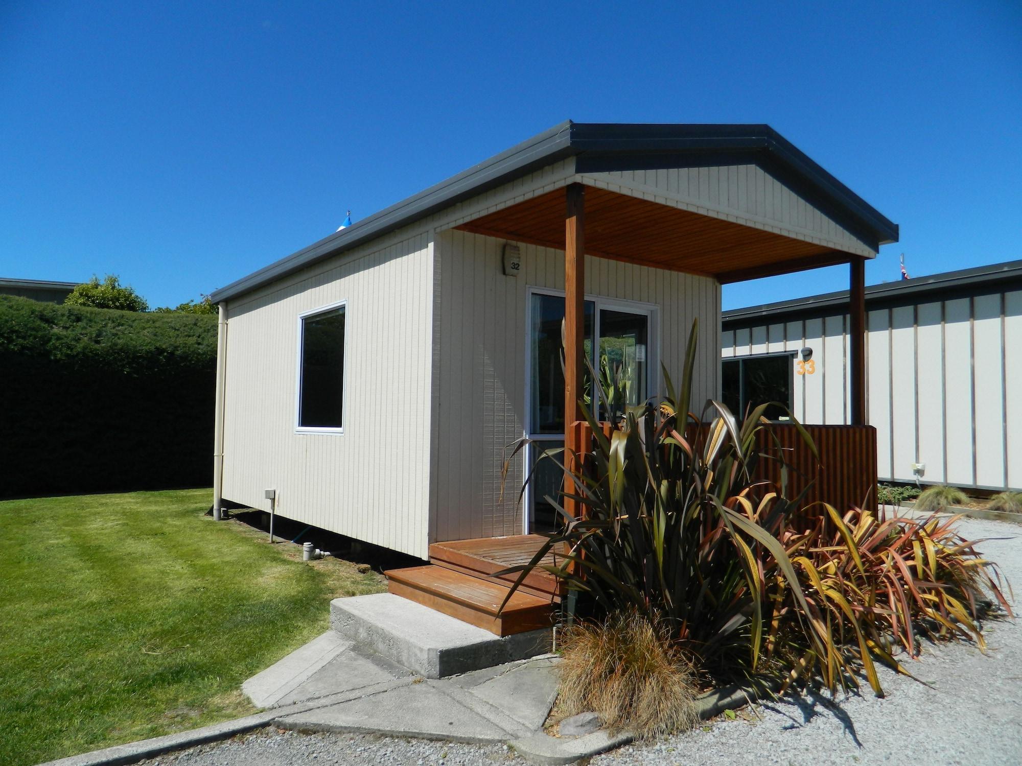 陶波德布雷思汽车旅馆 外观 照片 The photo shows a small, modern cabin or vacation home. It features a light-colored exterior with a a small porch at the entrance. The porch has wooden steps that lead up to the front door. Surrounding the cabin is a neat lawn, with some landscaping 