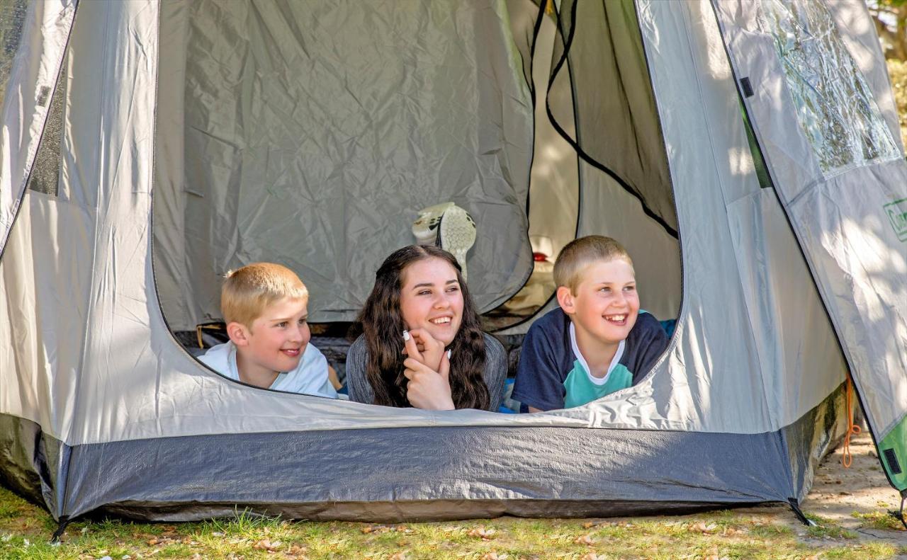 陶波德布雷思汽车旅馆 外观 照片 The photo shows three children inside a tent, looking out from an opening. Two boys are on the left, one with short blonde hair and the other with light brown hair, while the girl in the middle has long dark hair. They all appear to be happy and enga