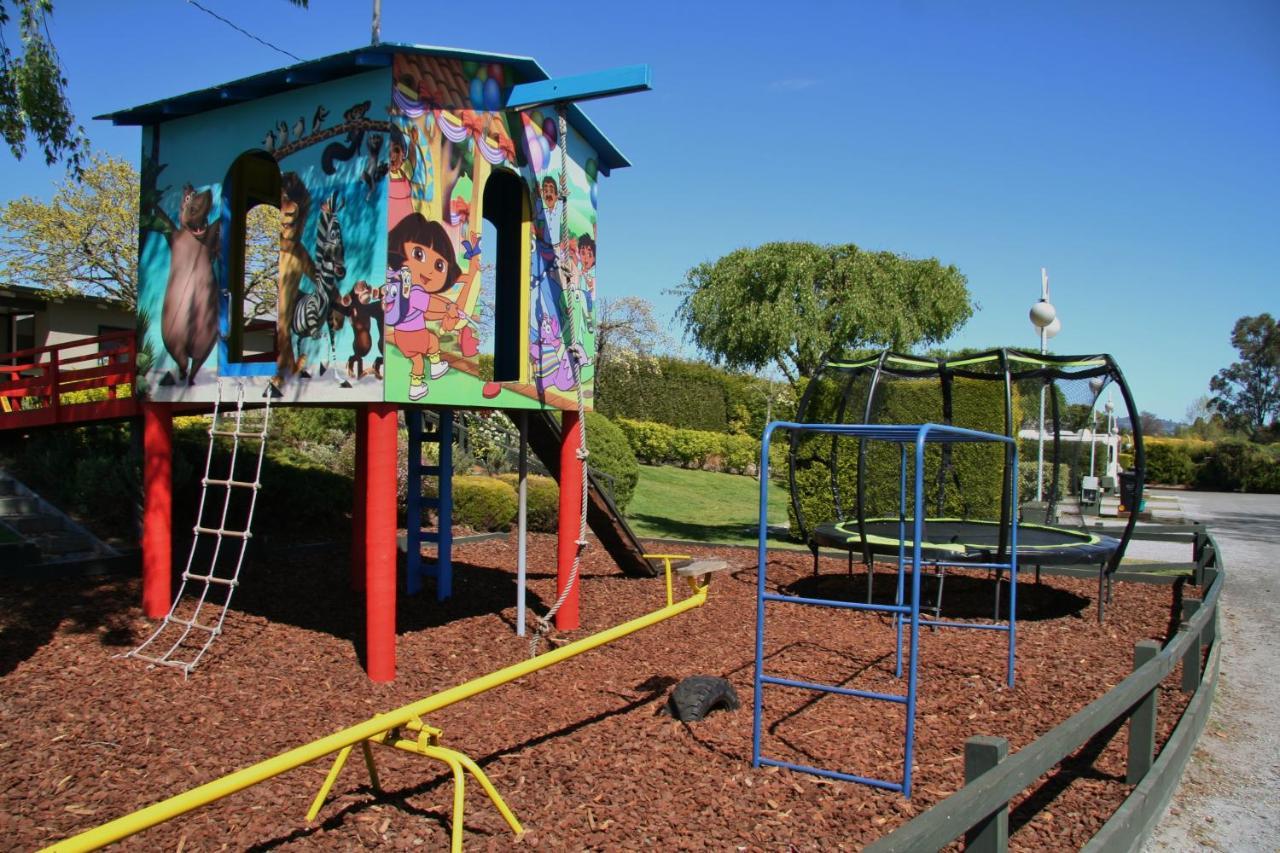 陶波德布雷思汽车旅馆 外观 照片 The photo shows a colorful playground structure that resembles a small house. It features a mural with animated characters on one side, likely including familiar children's figures. The house has ladders for climbing and a slide. Nearby, there is a c